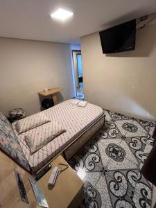 um pequeno quarto com uma cama e uma televisão em Hotel Fragata em São Miguel Paulista