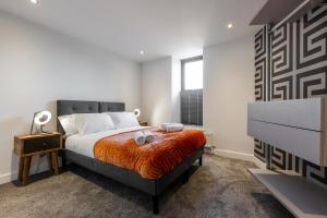 a bedroom with a bed with an orange blanket at Victoria Place - 3-bed apartment, parking, Wi-Fi in Hyde