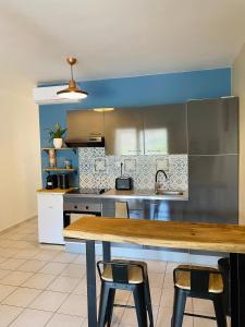 eine Küche mit einem Holztisch und 2 Hockern in der Unterkunft Appartement cosy à Grand Case, proche aéroport. in Grand Case