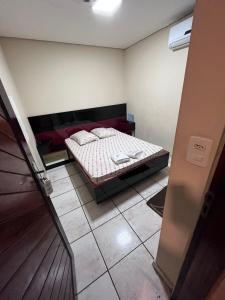 a small bedroom with a bed and a tiled floor at Hotel Fragata in São Miguel Paulista