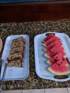a plate with a slice of cake and a slice of watermelon at Pousada Exuberante in Abraão