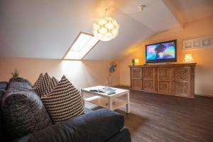 a living room with a couch and a tv at Berg Hotel Weingarten Garni in Rimsting