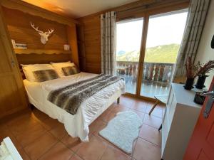 een slaapkamer met een bed en een groot raam bij Appartement COSY à Praloup, 43m2, vue magnifique in Uvernet