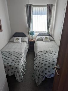 two beds in a small room with a window at Tide Away Anderby Creek in Anderby