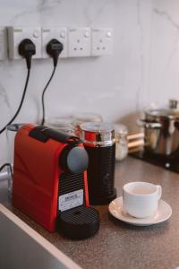 a red toaster sitting on a counter next to a cup at Petronella Suites Apartment @ Jesselton Quay in Kota Kinabalu