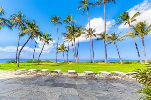 a row of chairs and palm trees on the beach at Hale Kai O Kihei in Kihei