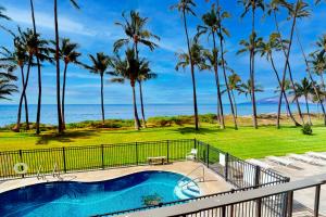 a pool with palm trees and the ocean in the background at Hale Kai O Kihei in Kihei
