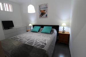 une chambre avec un lit avec des oreillers verts et une télévision dans l'établissement Loft, à Adeje 33 autres photos