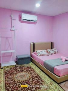 a bedroom with a bed and a pink wall at Pink Homestay D'Perlis in Kangar