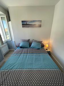 een slaapkamer met een bed met een blauw dekbed bij Appt FOURAS Centre Ville 50m de la Mer in Fouras