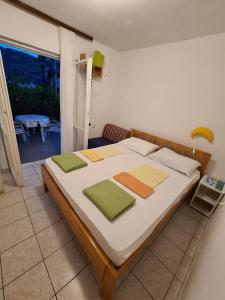 1 dormitorio con 1 cama grande con almohadas verdes y amarillas en Apartments Iva i Marko, en Marina