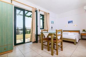 a bedroom with a table and a bed and a balcony at Dionysos Apartments & Studios in Stalida