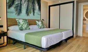 a bedroom with a large bed with a green blanket at Hotel Primavera Park in Benidorm