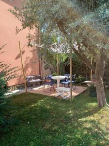 patio ze stołem i krzesłami pod drzewem w obiekcie A casa di Berta w mieście Pietrasanta
