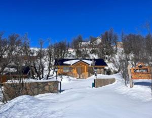 a cabin in the snow with a sign in front of it at Cabañas Viajeros Patagónicos Moquehue in Moquehue