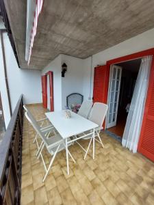 Biały stół i krzesła w pokoju z czerwonymi drzwiami w obiekcie Apartment Pineta dell'Alben Self Check in w mieście Serina
