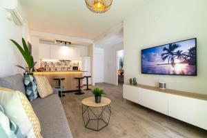 ein Wohnzimmer mit einem Sofa und einem Fernseher an der Wand in der Unterkunft NUEVO a estrenar. Vistas al mar, terraza, ascensor in Santa Pola