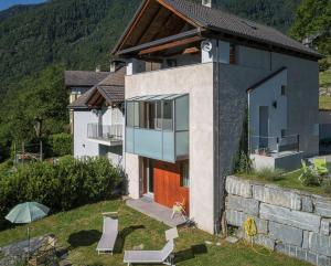 a house on a hill with chairs and an umbrella at Maison 4 soleil. Casa design luce e natura in Crodo