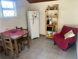 a kitchen with a table and a refrigerator and a chair at Chalé da Araucária in Campos do Jordão