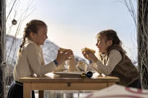 Zwei Mädchen sitzen am Tisch und essen Essen. in der Unterkunft Belambra Clubs Avoriaz - Les Cimes du Soleil in Avoriaz