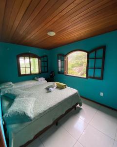 um quarto com uma cama numa parede azul em Chalé da Ana Aventureiro em Angra dos Reis