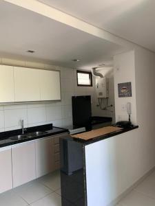 a kitchen with white cabinets and a black counter top at Eco Life Beach Class - Muro Alto Flat beira mar in Porto De Galinhas