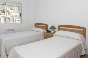 2 Betten in einem weißen Zimmer mit Fenster in der Unterkunft Frontalmar, Esc-A, 8º-29 in Cullera