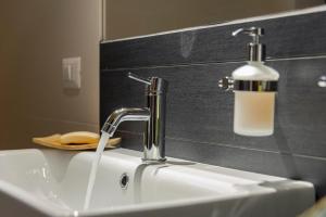 a bathroom sink with a faucet and a soap dispenser at Maison 4 jardin - Casa design ai margini del bosco in Crodo