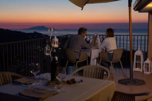 zwei Personen sitzen an einem Tisch auf einem Balkon bei Sonnenuntergang in der Unterkunft Villa Pane Resort in Sorrent