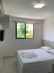 a white room with a bed with a window at Eco Life Beach Class - Muro Alto Flat beira mar in Porto De Galinhas