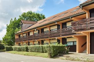 a building with a hedge in front of it at Kyriad Tarbes Bastillac in Tarbes