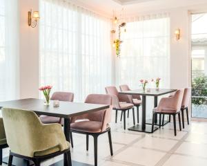two tables and chairs in a room with windows at Merci Boutique Hotel in Krakow