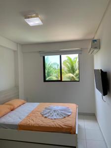 a bedroom with a bed with a window and a television at Eco Life Beach Class - Muro Alto Flat beira mar in Porto De Galinhas