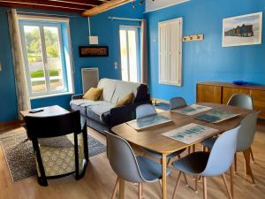 ein Wohnzimmer mit einem Tisch, Stühlen und einem Sofa in der Unterkunft L'hippocampe - appt mezzanine centre d'Arromanches in Arromanches-les-Bains