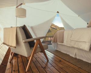 ペトロポリスにあるGlamping Cabanas do Valeのベッドルーム1室(ベッド1台、テント内の椅子付)
