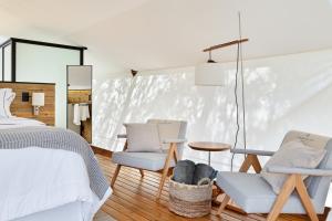 a bedroom with a bed and two chairs and a table at Glamping Cabanas do Vale in Petrópolis