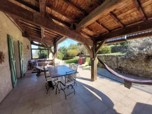 un patio con mesa, sillas y hamaca en Maison de Sao en pierres, en Lablachère