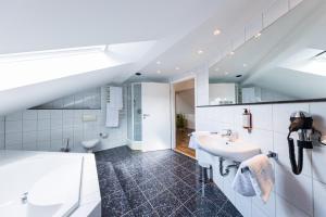 a white bathroom with a sink and a tub at Pension Sonne Appartements in Minden