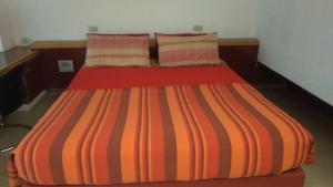 a bed with an orange striped comforter in a room at Milano 3 Apartment Pal Cigni in Basiglio