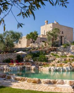 a house on a hill with a pool of water at Masseria San Paolo Grande in Ostuni