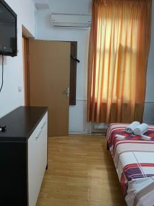 a room with a bed and a desk and a television at Budget Inn Amzei in Bucharest