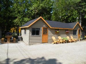 a cabin with chairs and a table in front of it at Bruce Anchor Motel and Cruises in Tobermory