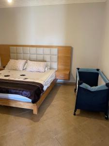a bedroom with a large bed and a chair at Villa avec Piscine, Terrain de Foot et Aire de Jeux pour Enfants in Bir Jedíd Saint-Hubert