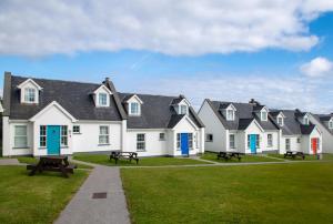 a row of white houses with blue doors and benches at Dingle Holiday Homes (S7) in Dingle