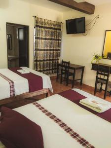 a hotel room with two beds and a television at Hotel Hacienda la Alborada in Tuxtla Gutiérrez