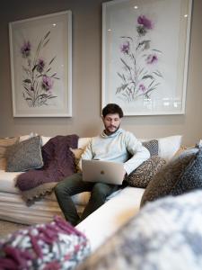 a man sitting on a couch with a laptop at Tunqueley Hotel in San Martín de los Andes