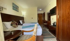 a hotel room with two beds and a desk at Delmar Hotel Matrouh in Marsa Matruh