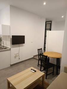 ein Wohnzimmer mit einem Tisch und Stühlen sowie einem TV in der Unterkunft COMPLEJO PINTA18 AT1, AT2 y AT3 in Sevilla