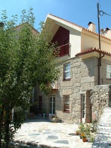 uma grande casa de pedra com uma árvore em frente em Casa do Meio da Vila em Loriga