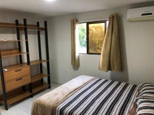 um quarto com uma cama e uma estante de livros e uma janela em Apartamento aconchegante no Bessa em João Pessoa